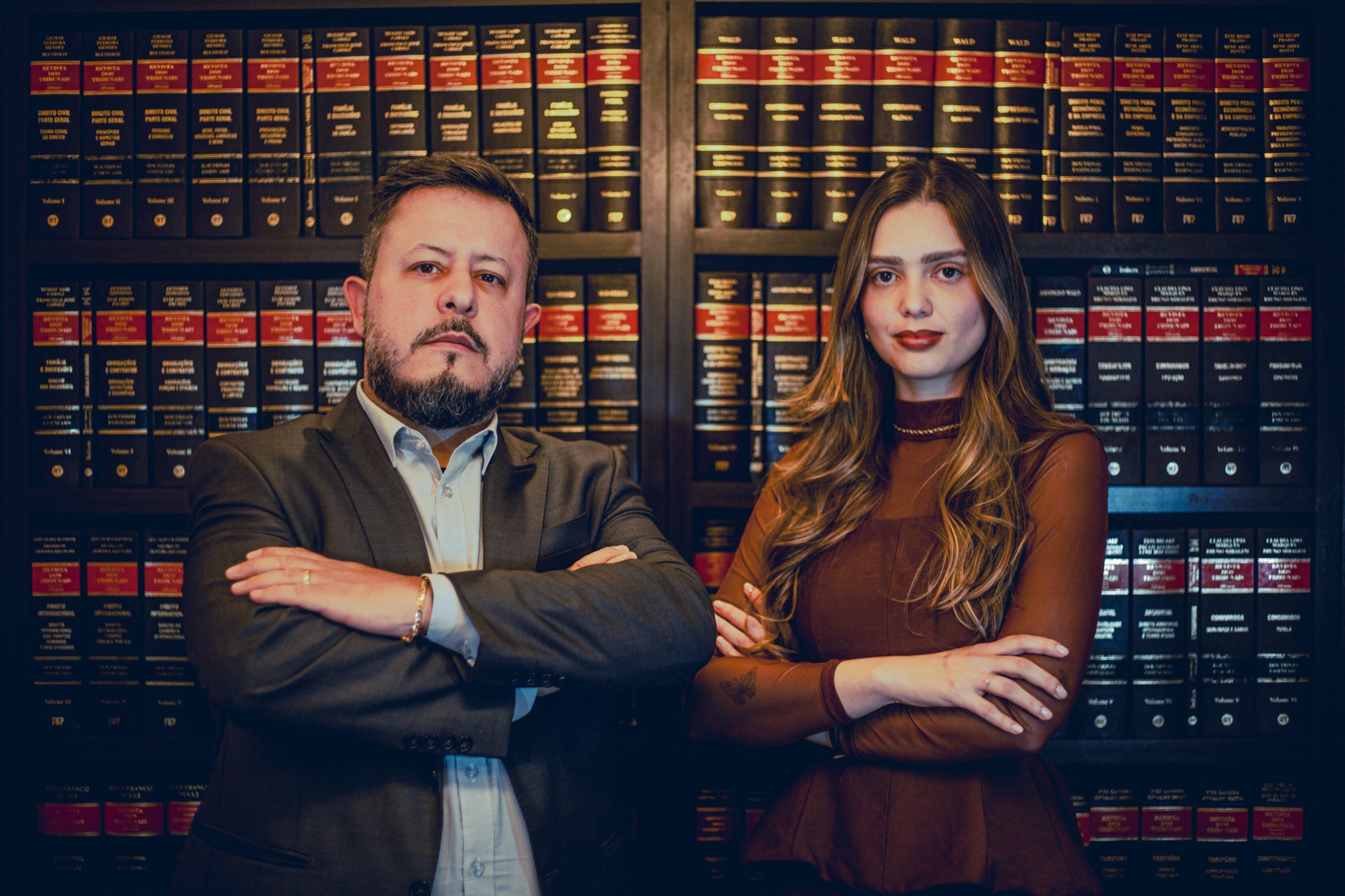 Gemerson Junior da Silva e uma mulher em frente a uma estante de livros jurídicos
